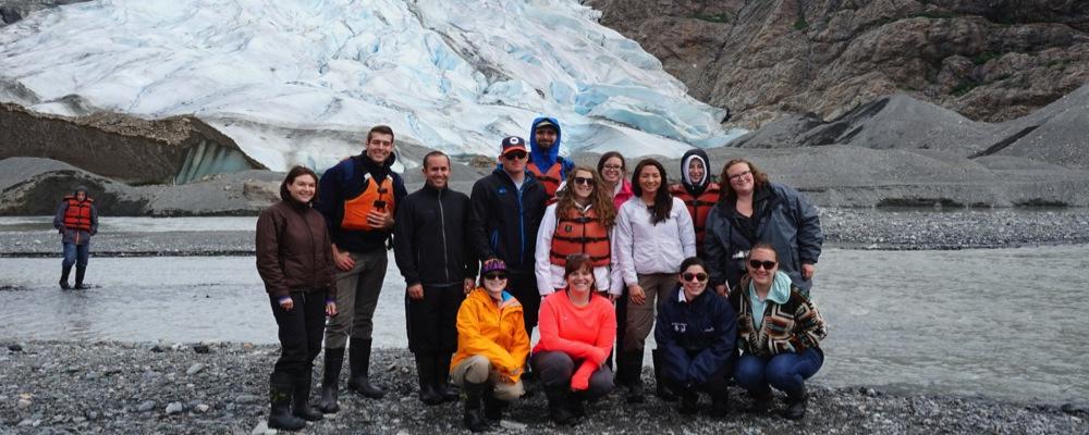 group picture of 2 instructors and their students in front of a glacier in alaska